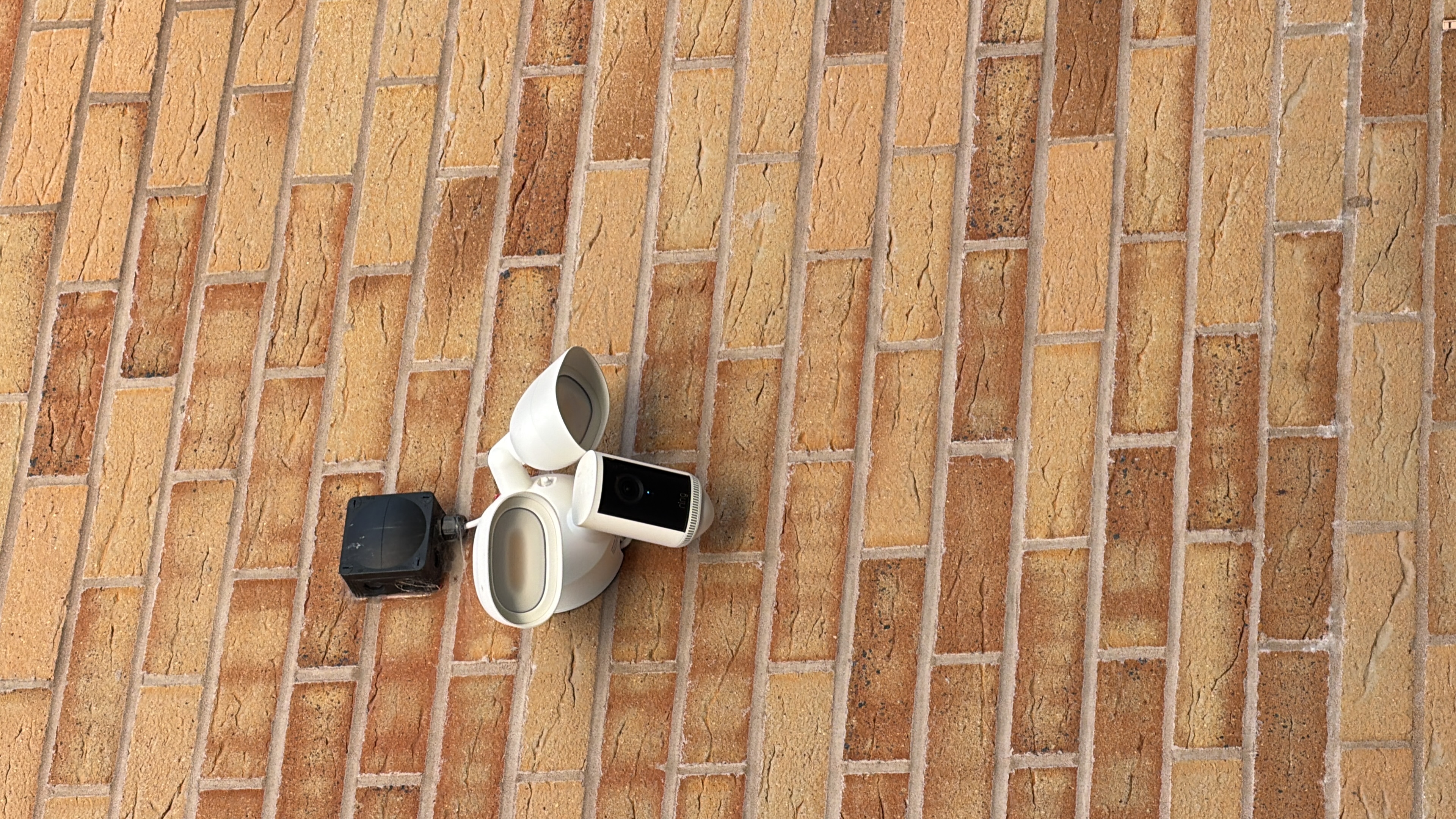 Floodlight camera installation on a brick wall