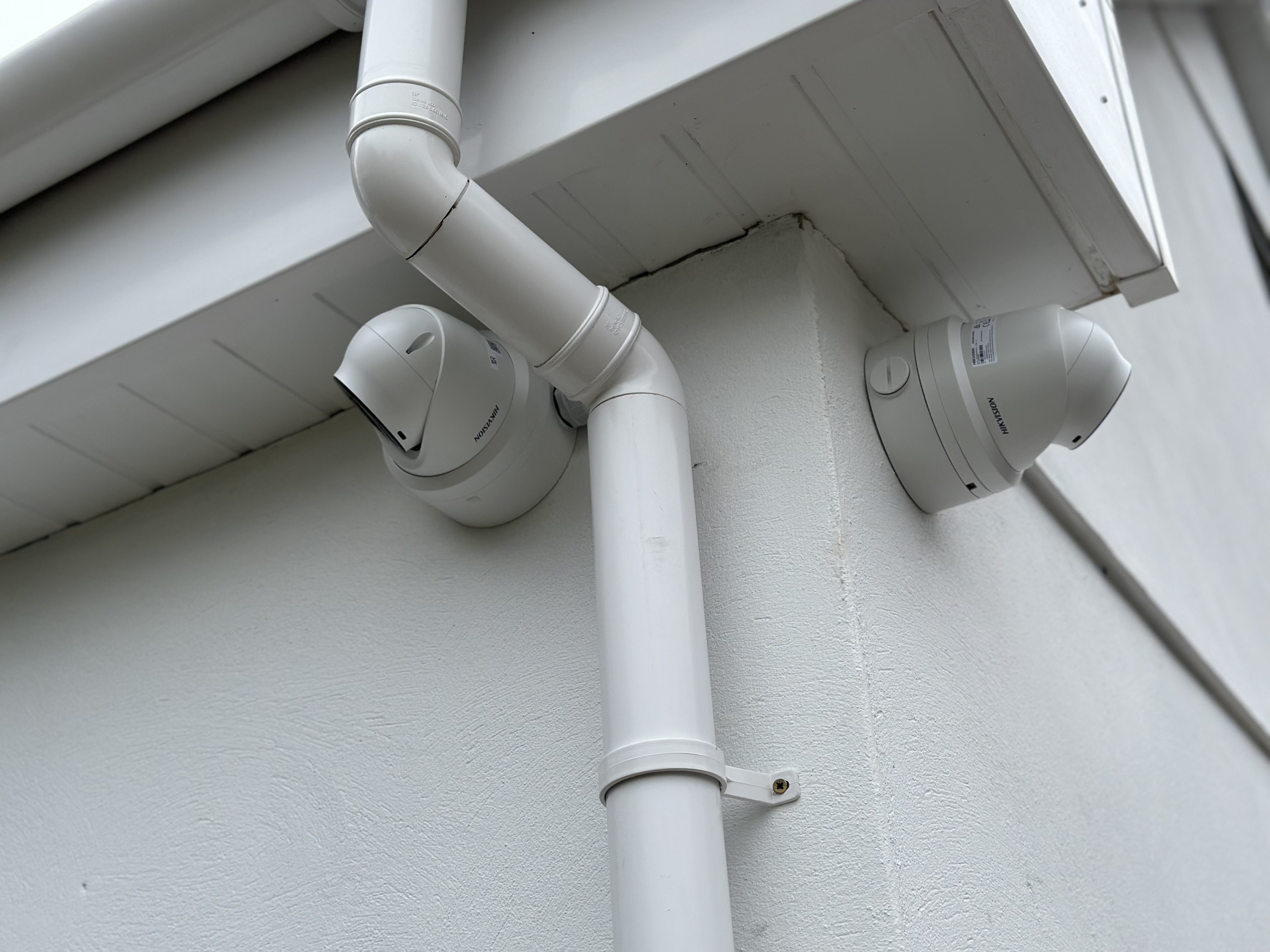 Two security cameras positioned around exterior drainage